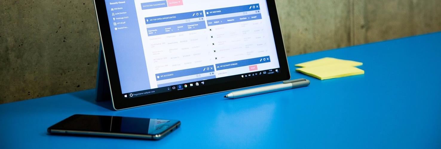 Ipad con Suite CRM, boli y postic sobre una mesa azul