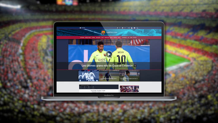 Web del FCB en un PC portátil y fondo de pantalla con una imagen borrosa del estadio