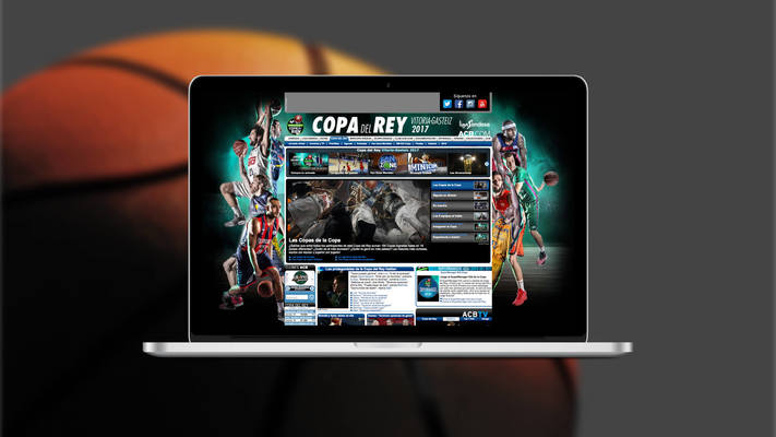 Web de l'ACB en un ordinador portàtil i fons de pantalla amb una pilota de bàsquet
